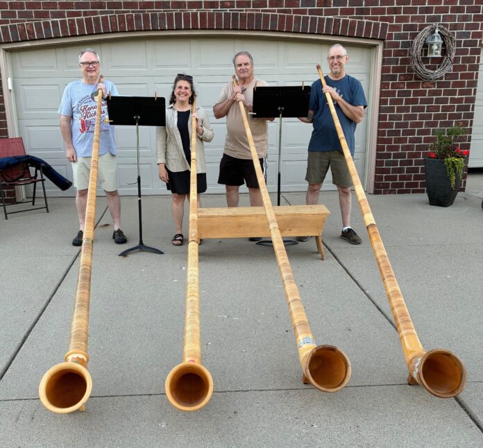 2026-07-03Kurt Amy Chuck and Todd mit Alphorn Kurt Hackemer, Amy Laurson, Charles Dibley und Todd Cranson (v.l.n.r.), Musikprofessoren aus Vermillion, läuten mit Alphörnern das Festmahl zum Ratinger Stadtjubiläum ein. Foto: Privat