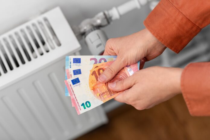 close up of hands with money on radiator at home Die Verbraucherzentrale NRW liefert Tipps für die kommende Heizsaison. Foto: Verbraucherzentrale